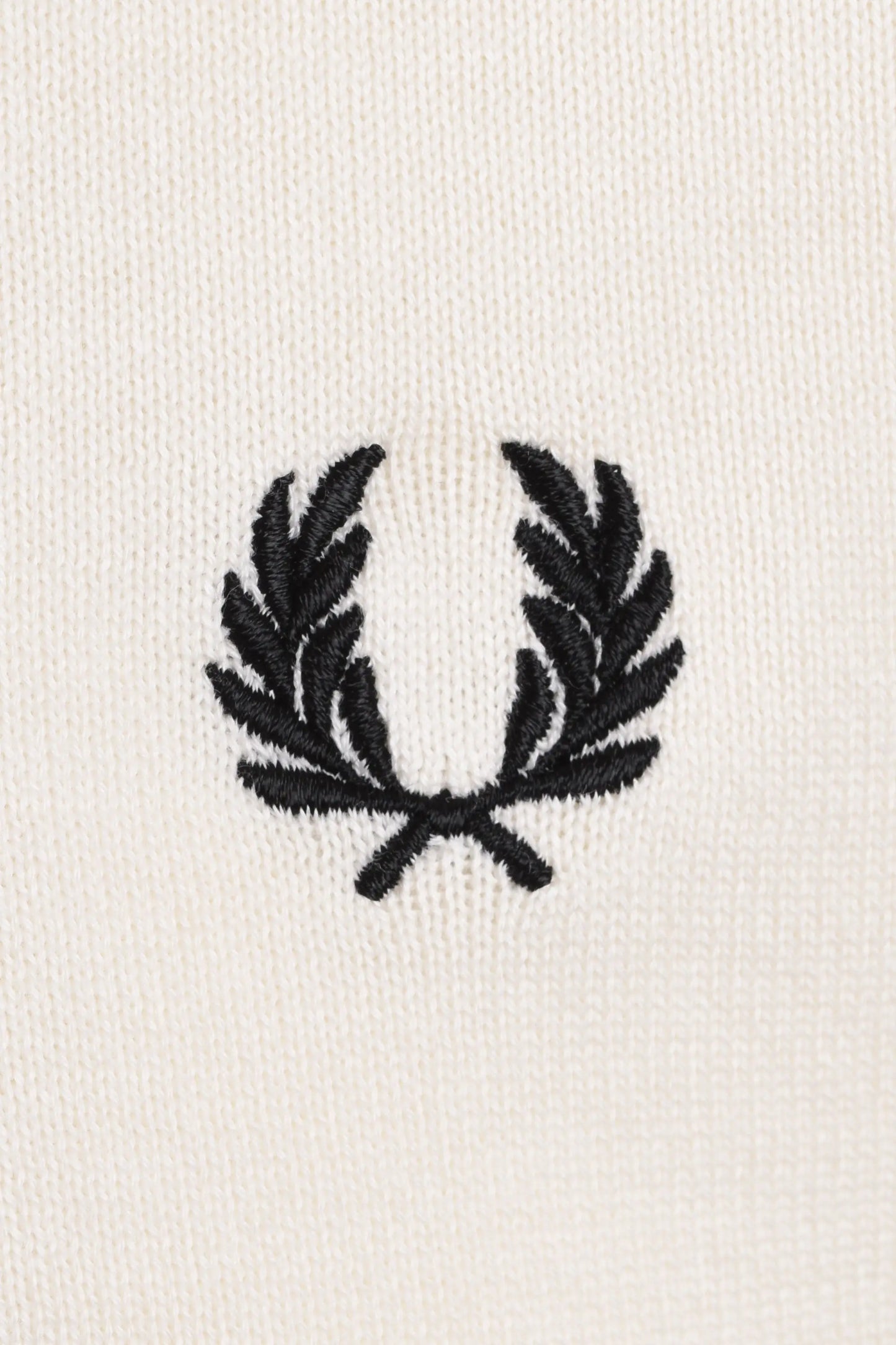 Black fred perry logo on a white polo close up