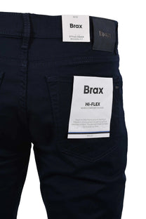 The back pocket of a pair of Brax Chuck cotton jeans in navy, the picture shows the branded leather patch on the back as well as the tags explaining about the jeans.