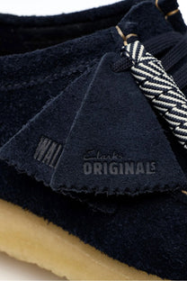 Close up of the suede branded tag on a pair of Clarks originals Wallabee shoe in the colour navy.