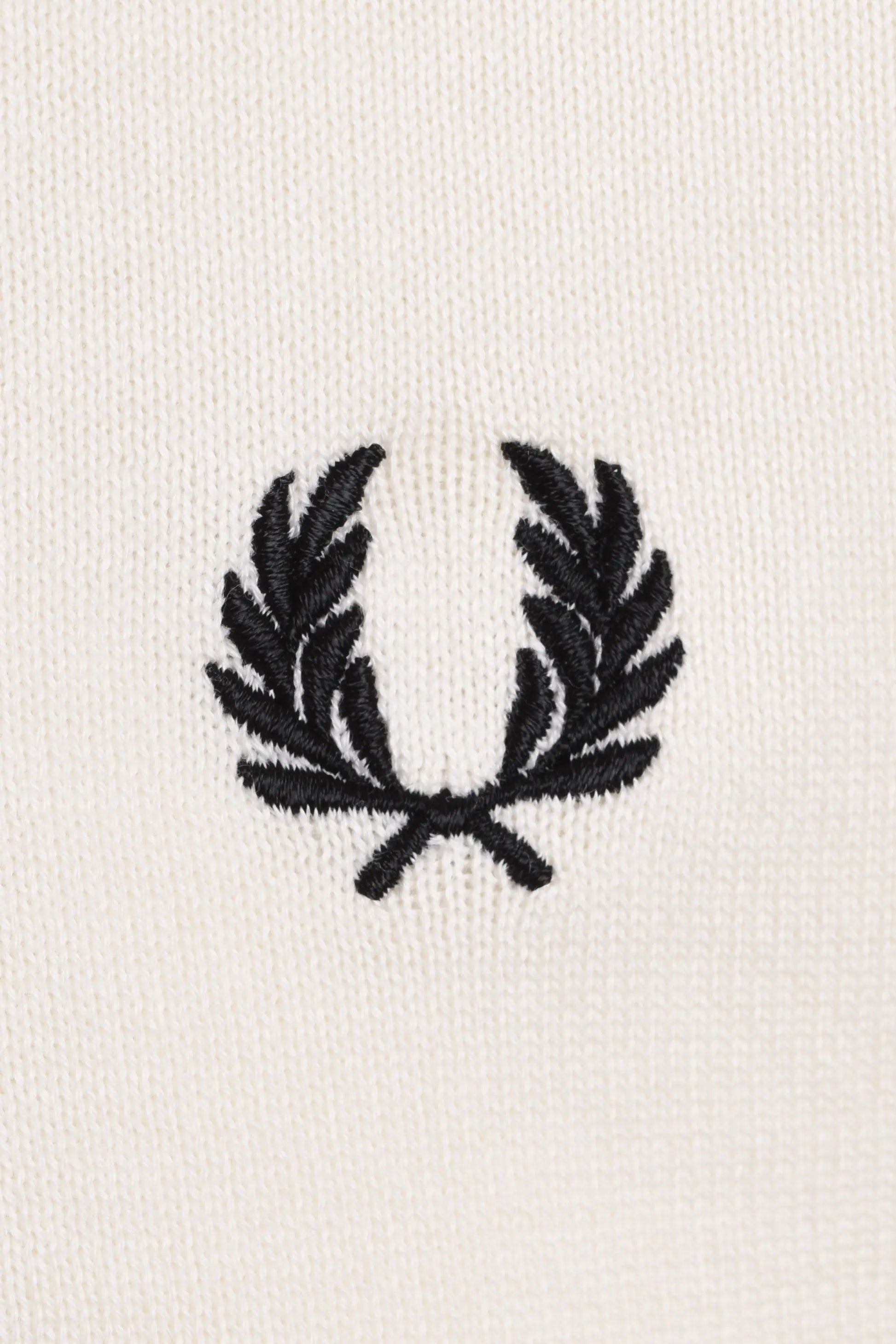 Black fred perry logo on a white polo close up
