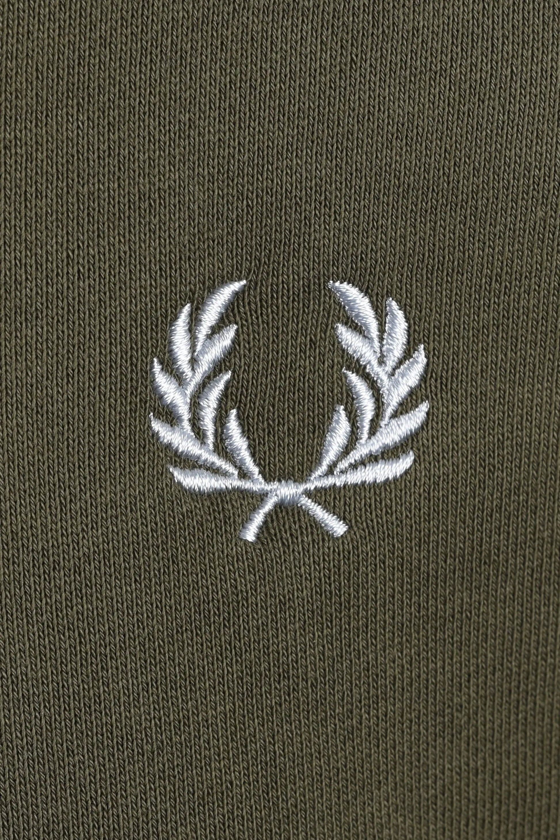 Close-up of a fred perry logo on a dark green sweatshirt