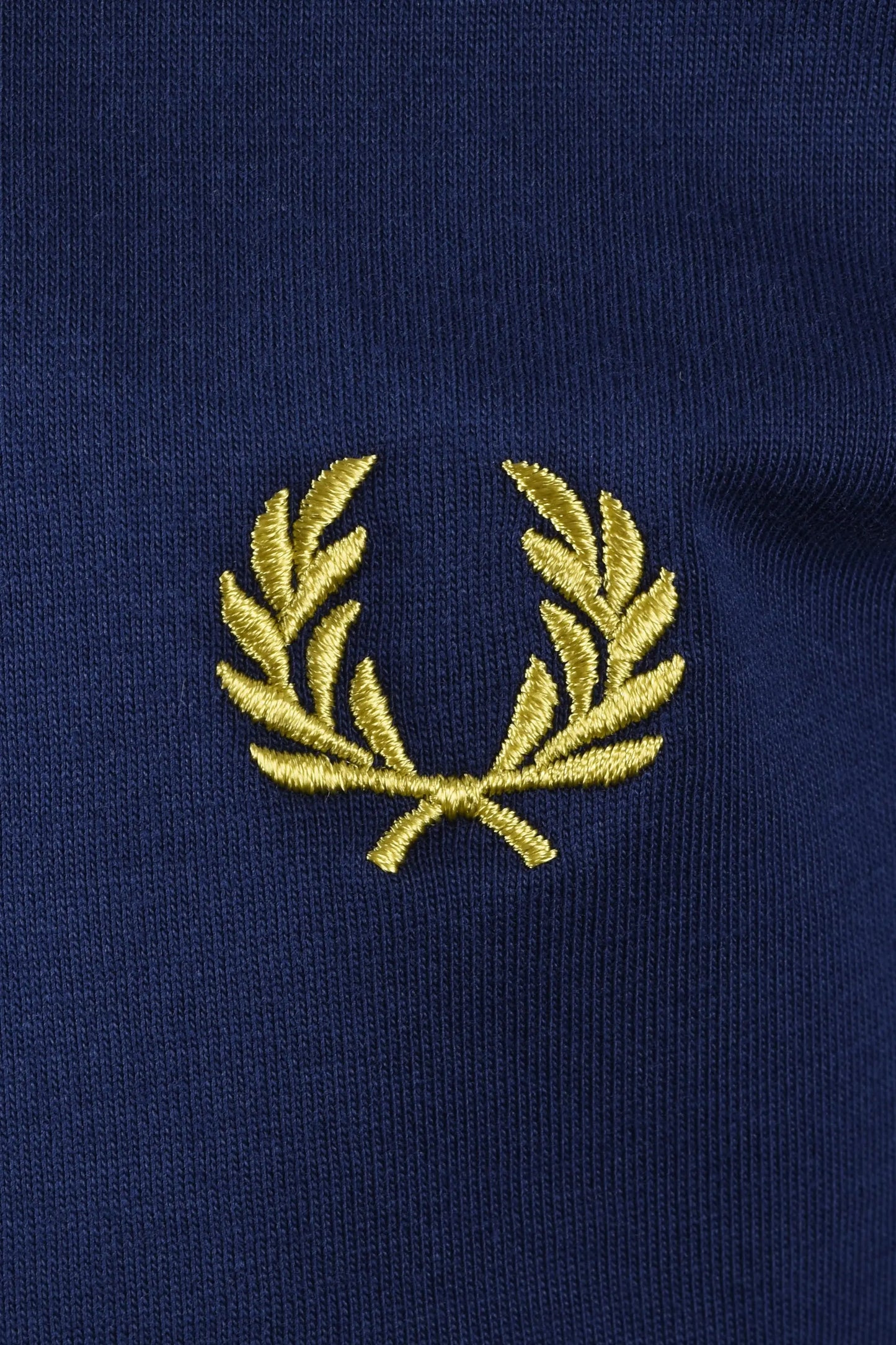 Close up of the embroidered Fred Perry laurel wreath logo in the colourways French navy.