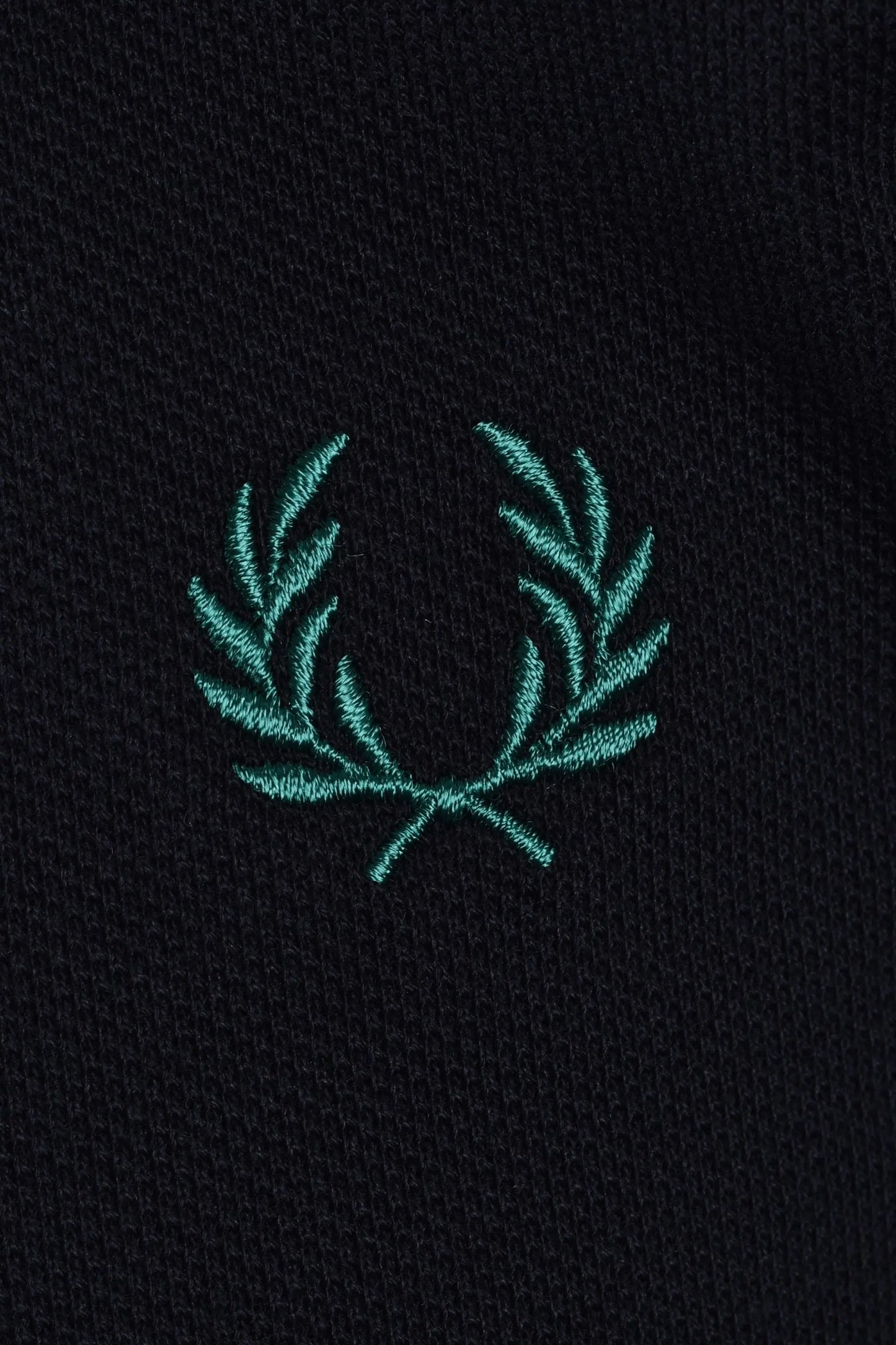 Teal embroidered fred perry logo on a navy polo