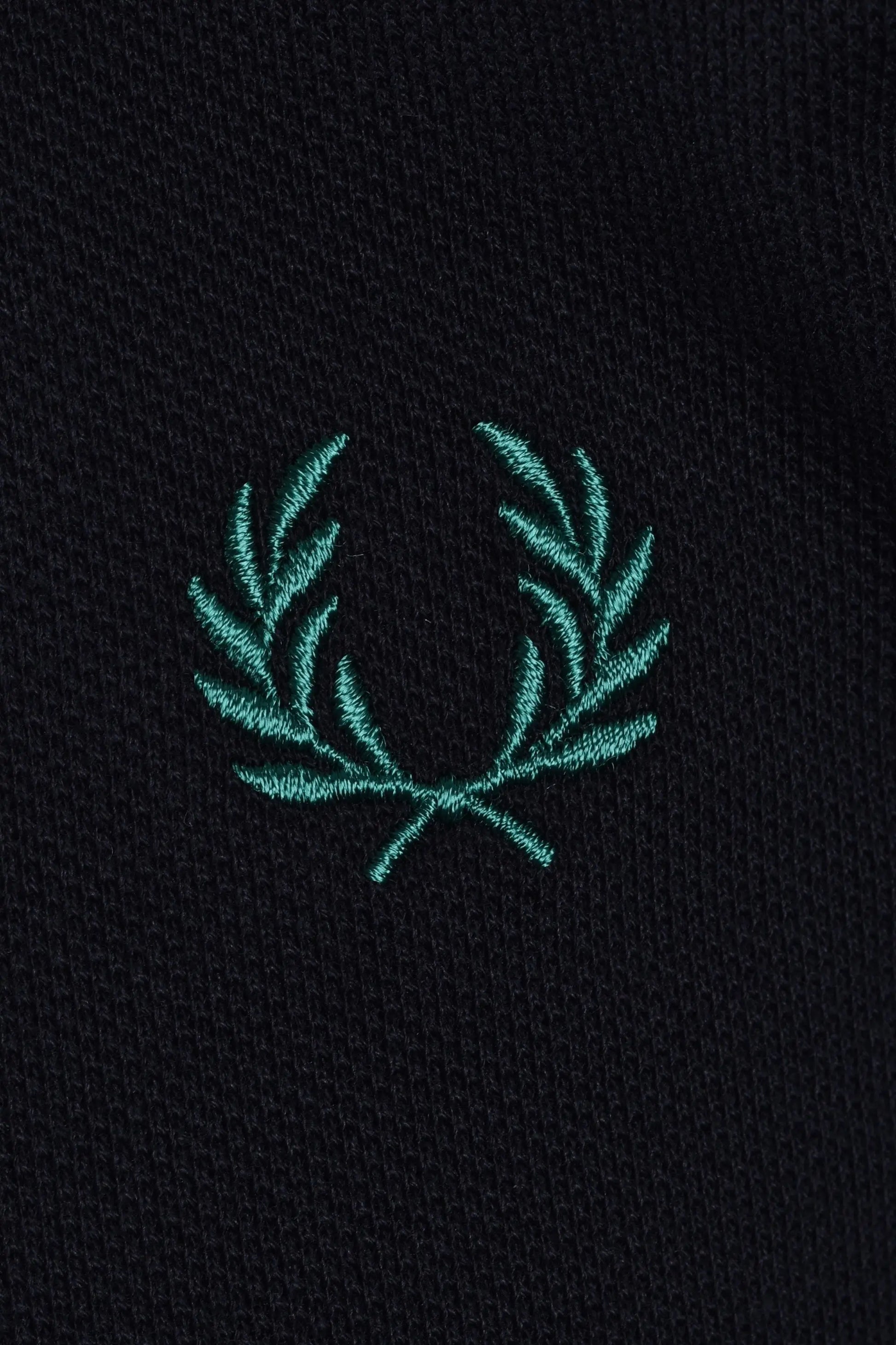 Teal embroidered fred perry logo on a navy polo