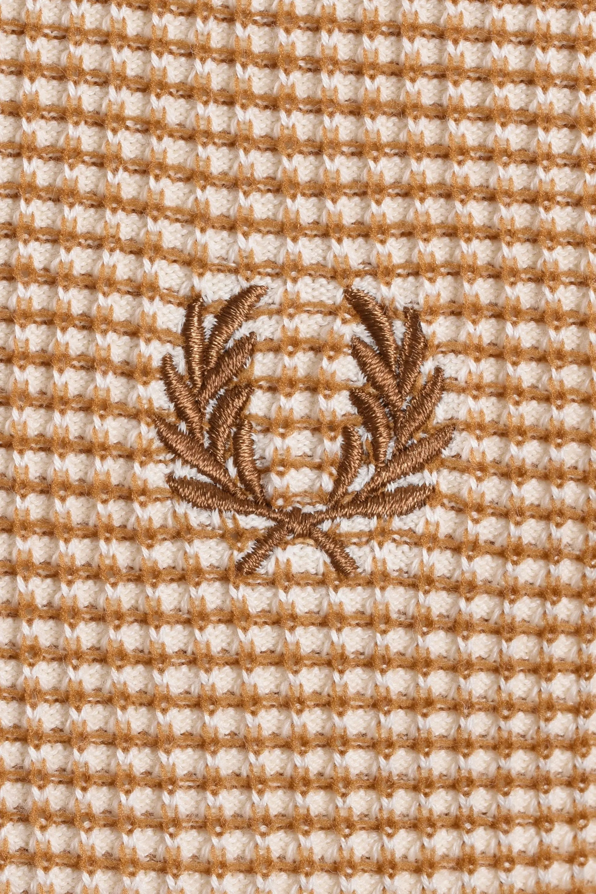 Close up of the Fred Perry laurel wreath logo embroidered on a textured waffle knit fabric in the colour tonic.