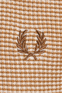 Close up of the Fred Perry laurel wreath logo embroidered on a textured waffle knit fabric in the colour tonic.