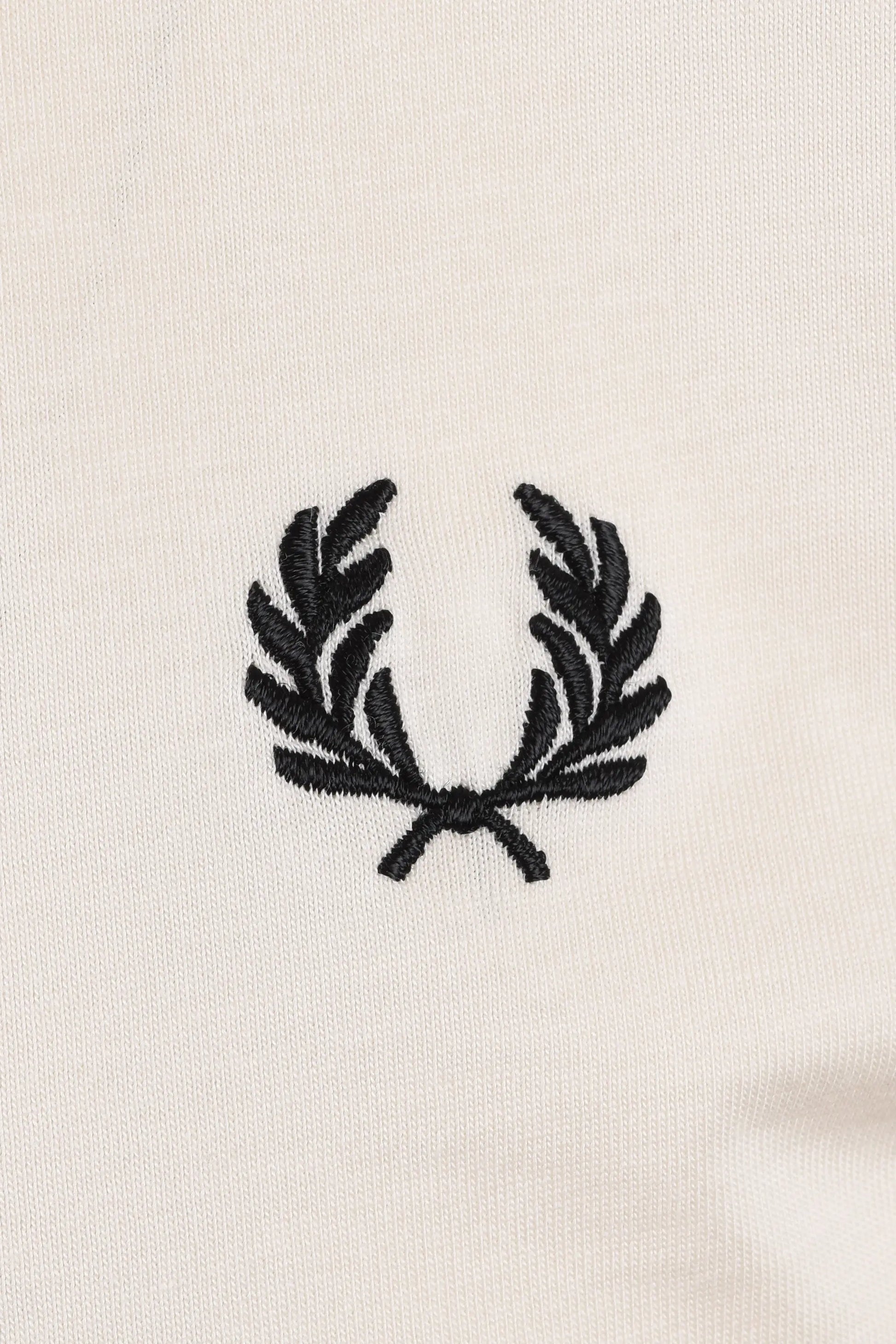 Black Fred Perry logo on a white t-shirt close up