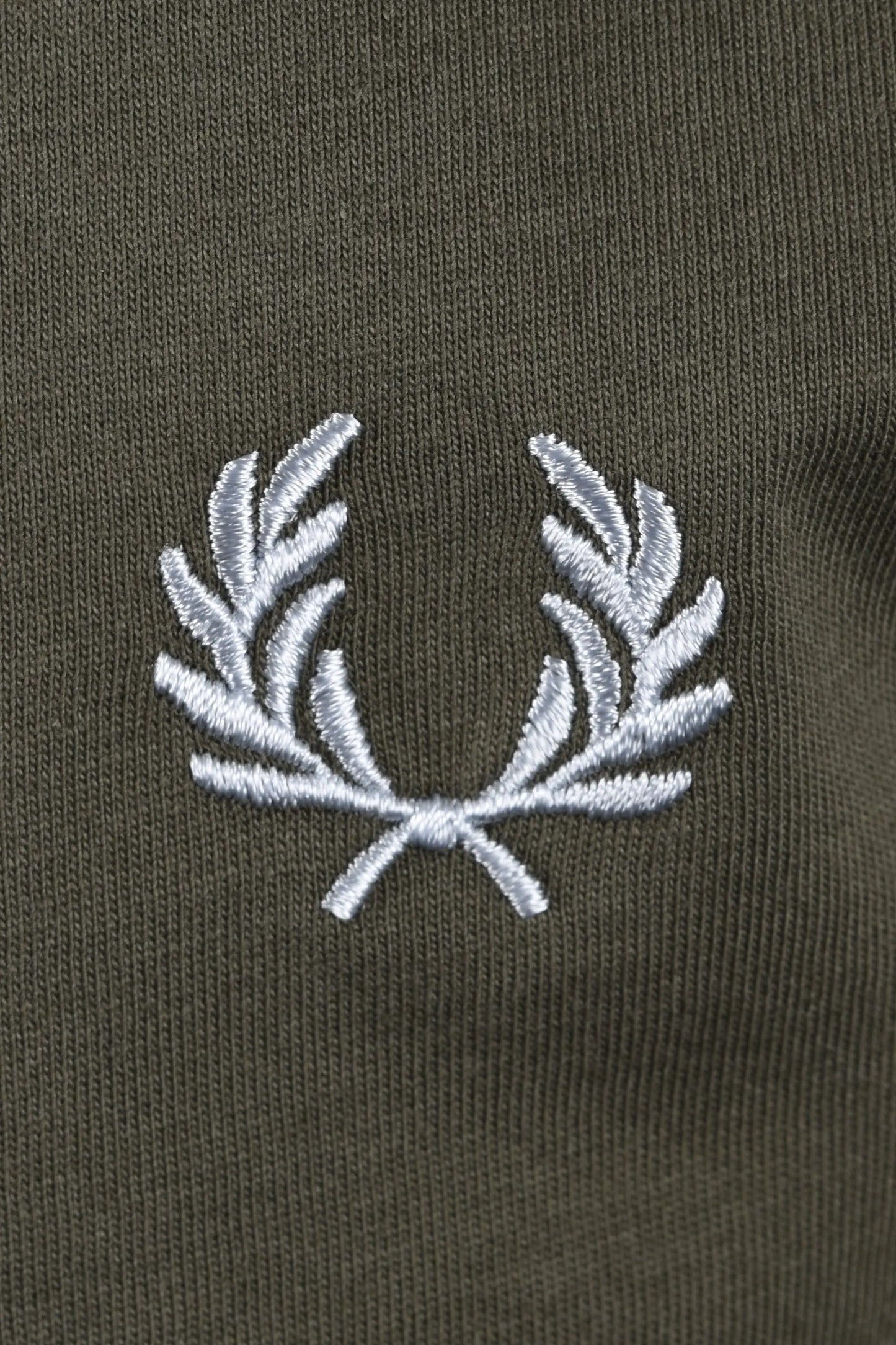 Close-up of a fred perry logo on a dark green background