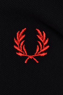 red fred perry logo on a black polo close up 