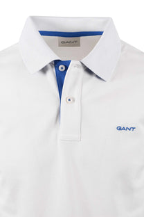 Close up of the collar and placket of a Gant polo-shirt featuring a bold blue tone on the underneath of the placket and an embroidered Gant logo on the chest.