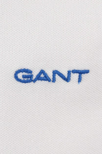 Close up of the Gant embroidered logo in blue upon a white textured background.