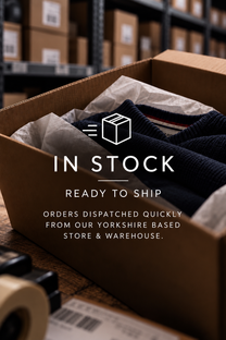 A brown cardboard shipping box filled with a dark navy knit garment and tissue paper, with overlaid text reading 'IN STOCK READY TO SHIP ORDERS DISPATCHED QUICKLY FROM OUR UK WAREHOUSE.' The background shows blurred warehouse shelves and boxes.
