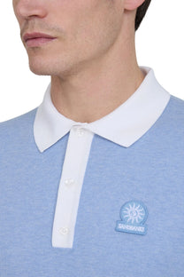 Close-up of a blue sandbanks polo shirt with a white collar and a visible brand logo.