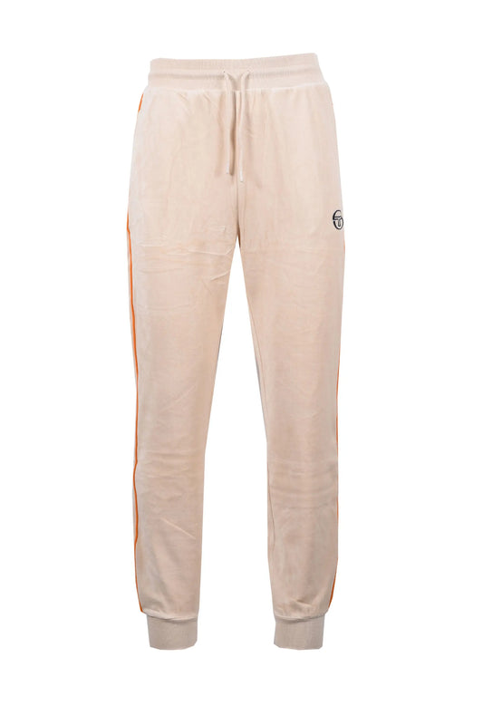 Full length picture of the Sergio Tacchini tack pants in a velour fabric. Salmon pink coloured material with a stricking bright orange piping along the leg.