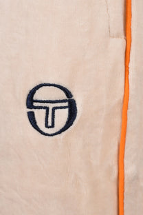 Sergio Tacchini embroidered logo on top of a neutral coloured velour fabric with orange piping detail down the side.