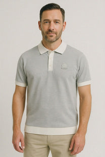 A man wearing a grey and white knitted polo shirt by the brand Sandbanks.
