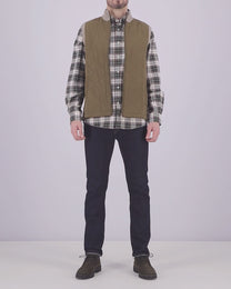 Video of a man wearing a Barbour tartan shirt layered with a gilet on top, with a pair of jeans and trainers